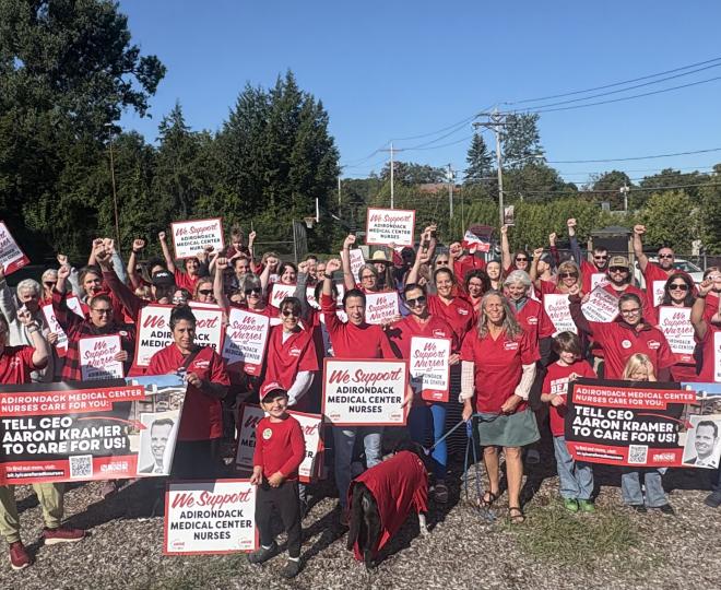Adirondack Medical Center nurses pose with signs after re-hanging banners for a fair contract.