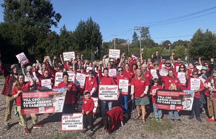 Adirondack Medical Center nurses pose with signs after re-hanging banners for a fair contract.