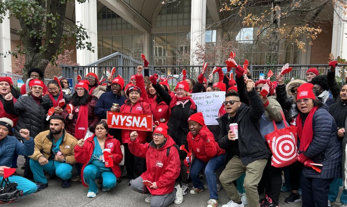 Group of nurses holding NYSNA signs and raising their fists