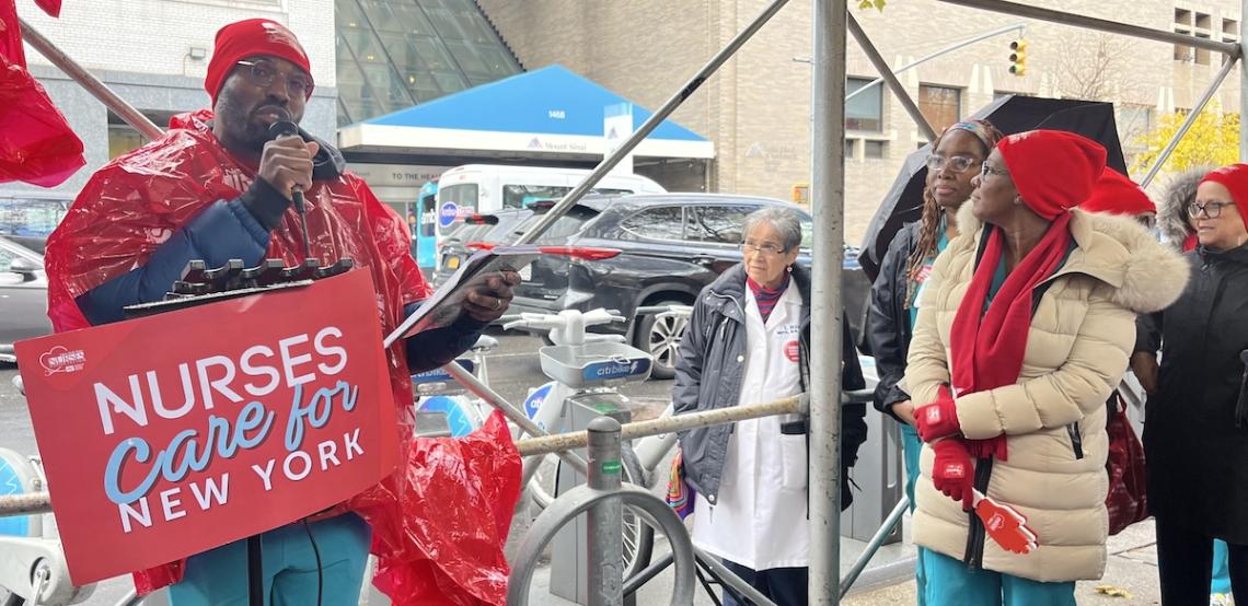 Speaker at a microphone behind a placard that says Nurses Care for New York