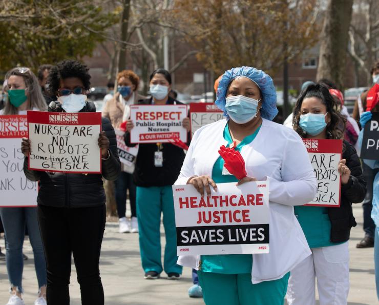 Nurses wearing masks holding signs demanding healthcare justice