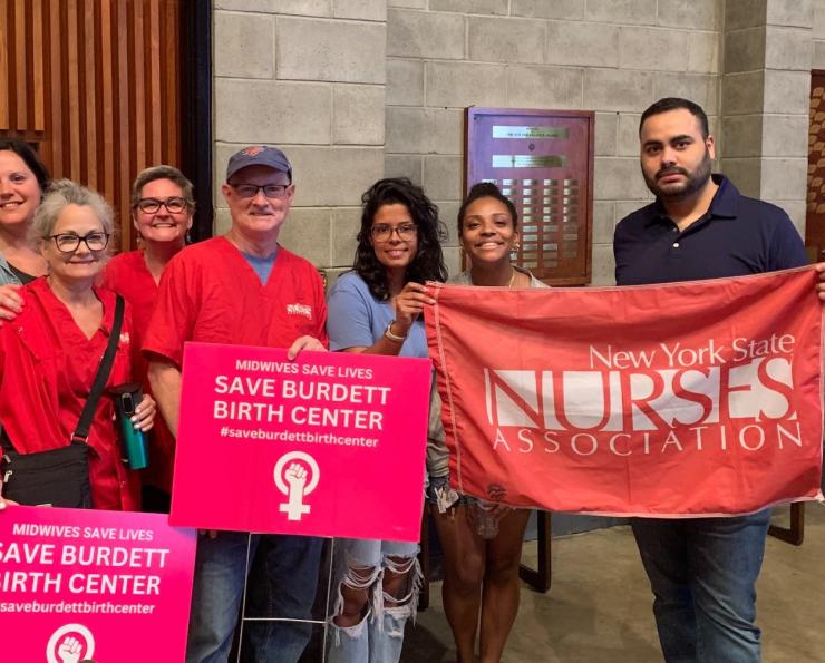 Nurses hold signs saying Save Burdett Birth Center and hold a NYSNA banner