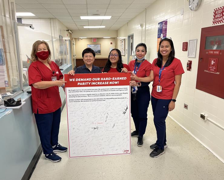 Elmhurst nurses hold a petition board demanding pay parity for NYC Health and Hospitals nurses