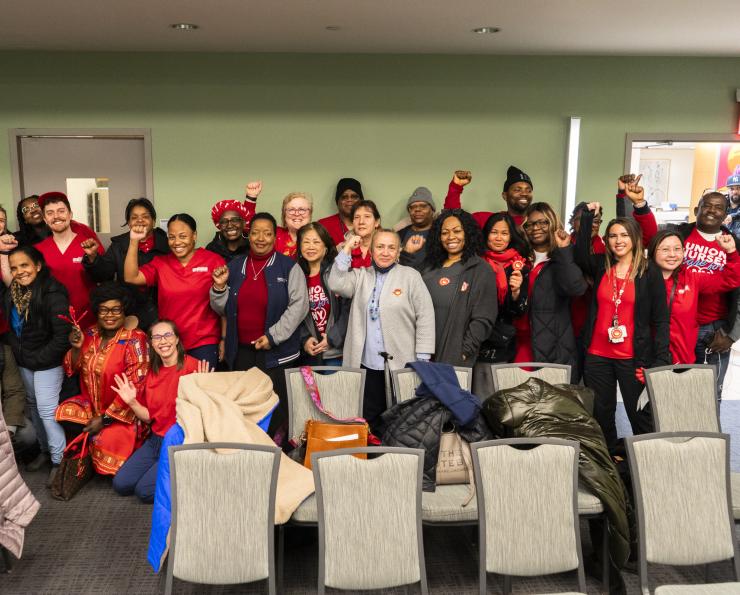 Group of nurses gathered together posing with raised fist.