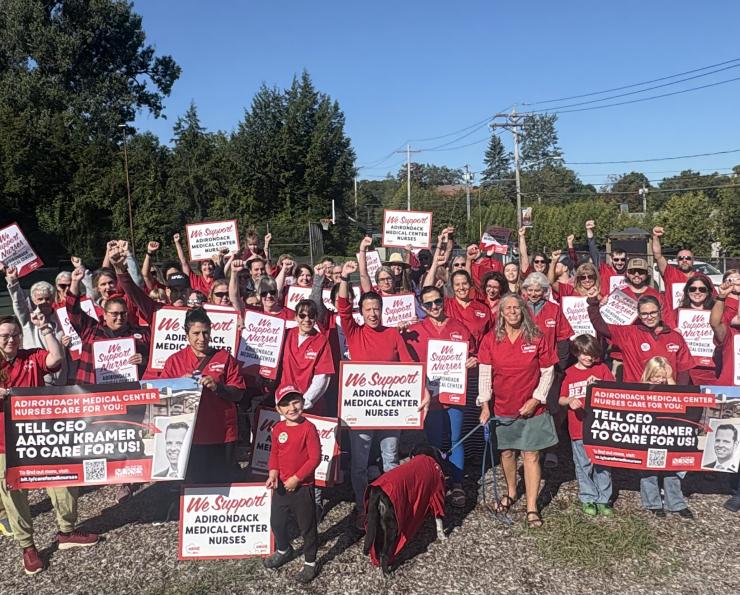Adirondack Medical Center nurses pose with signs after re-hanging banners for a fair contract.