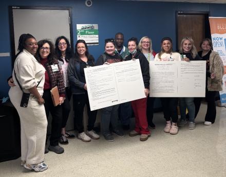 ECMC nurses deliver two big boards during a labor-management meeting